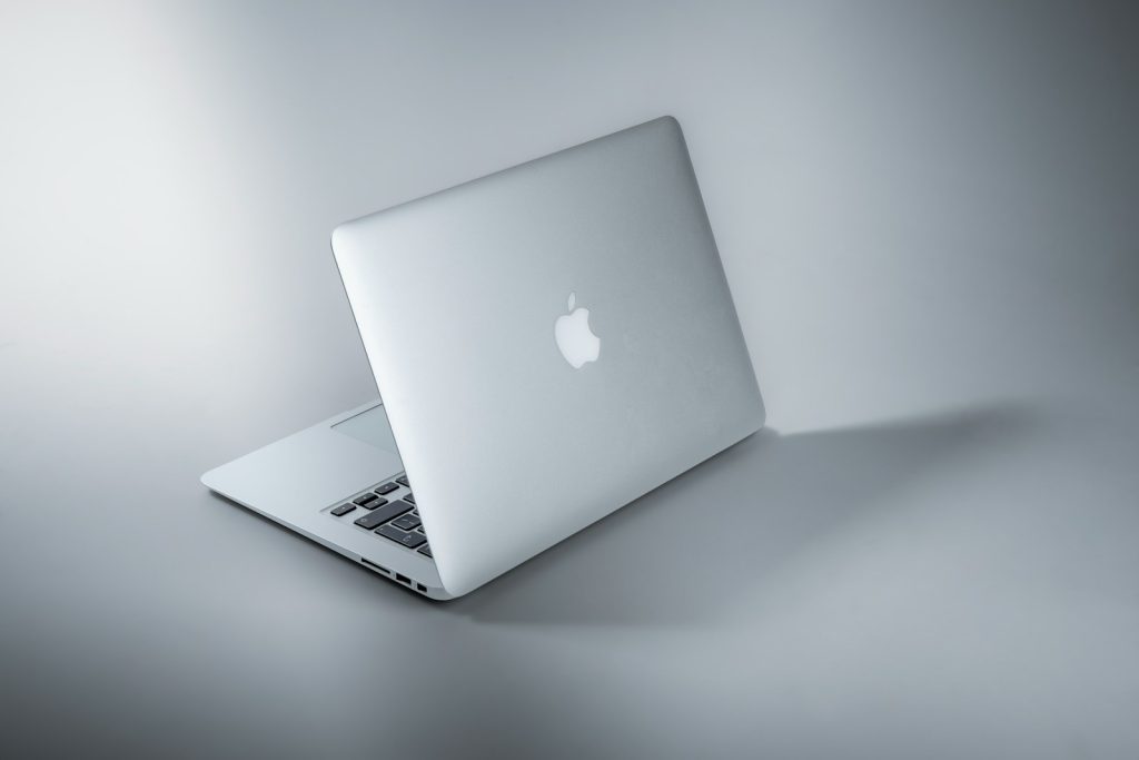 Sleek silver laptop on a grey background, partially open, showcasing an elegant and modern design