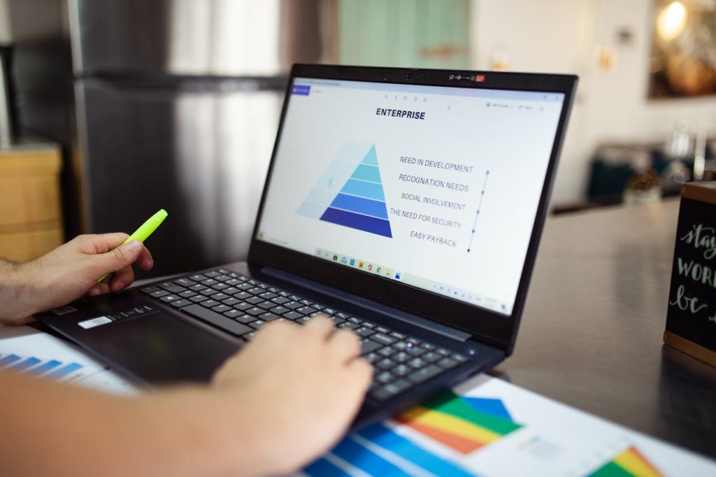 Person analyzes business data on laptop, using pyramid chart and financial reports